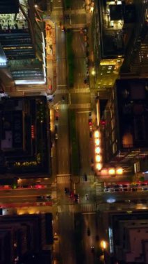 Geniş yollar güzel binaların sınırlarını çiziyor. Geceleri ışıkla dolu harika bir şehir. Kuş bakışı. Dikey video