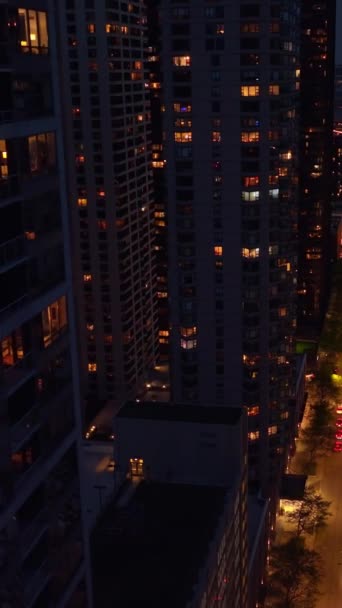 夜はシカゴのダウンタウンの明るい通り ドローン映像は 忙しい道路の上の素晴らしい超高層ビルの間に降下します バーティカルビデオ — ストック動画