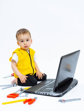 Genç bir çocuk dizüstü bilgisayarın önünde yerde oturuyor. Laptop açık ve siyah ekranı var..