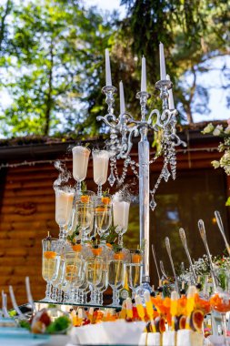 Uzun bir mum tutacağı ve bir bardak şampanyası olan bir masa. Mumlar yanıyor ve bardaklar şampanyayla dolu..