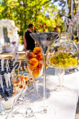 Çeşitli meyve ve içeceklerle dolu bir masa. Üstünde kırmızı meyve olan bir martini bardağı da dahil.