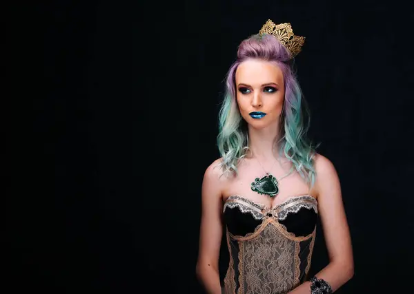 A woman in a black dress with a crown on her head. She has blue and purple hair