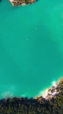 Yoğun ormanın ortasındaki turkuaz göl üzerinde nefes kesici bir manzara. Güzel manzarayla çevrili derin sular. Kuş bakışı görüş. Dikey video