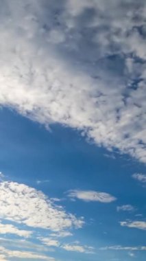 Güzel ışık bulutları uçup gider. Mavi gökyüzünü açar. Bulutlardan gelen güneş ışınları. Aşağıdan zaman ayarlı görüntü. Dikey video
