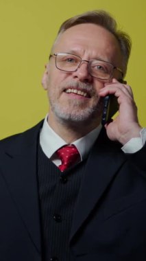 Telefonu olan kıdemli bir iş adamı. Stüdyoda zarif kostümlü bir adam cep telefonuyla konuşuyor ve kameraya bakıyor. Dikey video