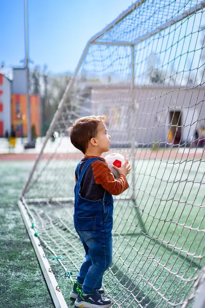 Seorang Anak Laki Laki Sedang Memegang Bola Dan Melihat Gol Stok Lukisan  