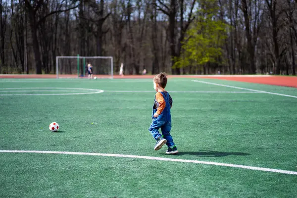 Молодий Хлопець Грає Футбол Полі Він Одягнений Синій Комбінезон Тримає Стокове Фото