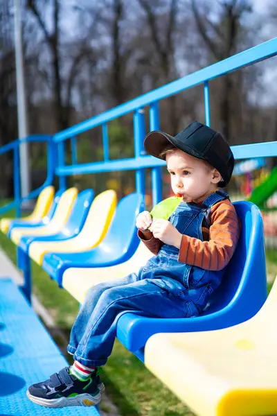 Seorang Anak Laki Laki Duduk Bangku Biru Dan Kuning Makan Stok Gambar