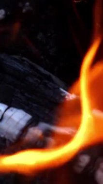 Şenlik ateşi. Turuncu alevlerde odun yakmak. Güzel ateş parlak bir şekilde yanar. Ateşin közleri yukarı tırmanıyor. Dikey video