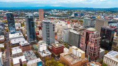 Portland, Oregon şehir merkezi, yüksek binalı mimarisi olan ABD. Şehrin alacakaranlık manzarası ve arka planda dağ siluetleri.