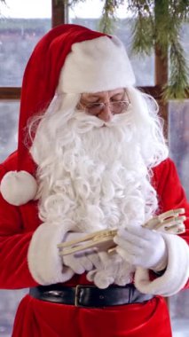 Noel Baba özel dekore edilmiş bir odada duruyor, yeni yıl ağacının yanında ahşap bir sevgili tutuyor. Noel ruhu konsepti portreyi kapatır. Noel arifesi. Yeni yıl yaklaşıyor. Dikey video