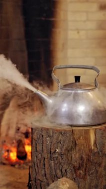 Kaynayan retro alüminyum çaydanlık. Çaydanlık buharı. Noel Baba kaynar su ısıtıcısını alır. - Yakın çekim. Kütüğün üstünde çaydanlık. Dikey video