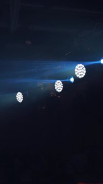 Gece kulübündeki parlak ışıkların arka planı. Konserde projektörlerden gelen ışınlarla ışık gösterisi. Yüksek çözünürlük Dikey video