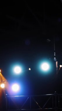 Kulübün içinde projektörlerin renkli ışıkları parlıyor. Karanlık oditoryumdaki spot ışıklarının mavi ve turuncu renkleriyle yanıp sönen ışınlar. Dikey video
