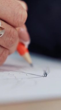 Güzel yüzüklü bir tasarımcı kadın atölyede elbise çiziyor. Kadın terzi masaya keskin bir kalemle çizer. Dikey videoyu kapat