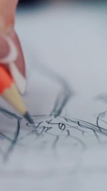 Kadın elleri şablona çizim yapıyor. Moda tasarımcısı kağıt üzerine kurşun kalemle bir elbise taslağı çizer. Çizim ve zanaat tasarımı. Yakın plan. Dikey video