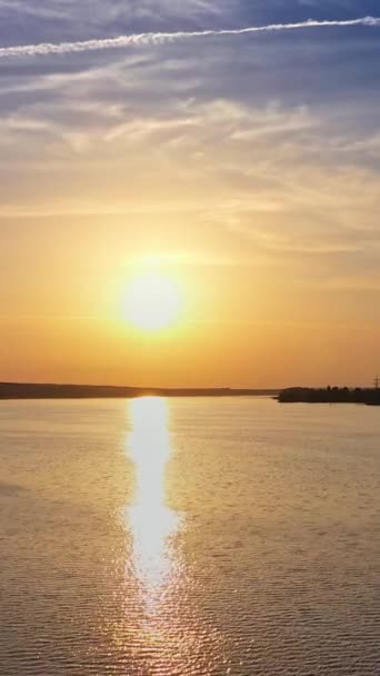 川面の夕日景観のドローン風景 太陽の反射で美しい夜の川 水の近くの植物からの煙が付いている産業管 カメラが下に移動する バーティカルビデオ — ストック動画