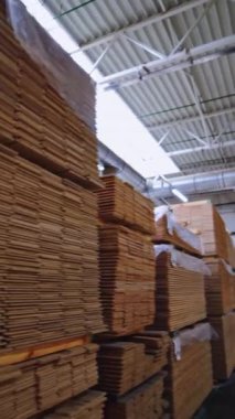 Atölyede yığınla lamine zemin paneli var. Parke tahtası üretimi için bir fabrika. Modern endüstriyel ahşap fabrikası. Dikey video