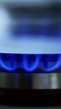 Mutfak ocağı kapanıyor. Ocağın yanındaki ocakta mavi alev. Doğal gaz yanmayı durdurur. Yakın plan. Dikey video