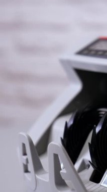 Kadın veznedar nakit para sayma makinesine para koyuyor, dikey videoyu kapatıyor