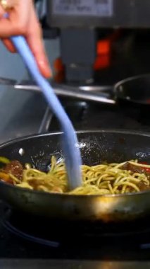Kızartma tavasında kırmızı domates ve mantarla spagettiyi pişirip karıştırmak. Bir yandan video. Dikey video