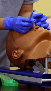 Sıhhiye, tıbbi bir mankenin burnuna nasıl oksijen tüpü yerleştirileceğini gösteriyor. Gerekli aletleri elinde tutan uzman bir doktor. Dikey video