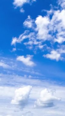 Cennetteki güzel mavi gökyüzü, üzerinde beyaz bulutlar yüzüyor. Kümülüs ve dönen bulutlar atmosferde dönüşüyor. Zaman ayarlı. Dikey video