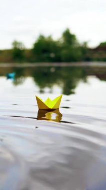 Nehirde dalgalar üzerinde yüzen kağıt bir gemi. Origami Kağıt Tekne Dikey Videosu