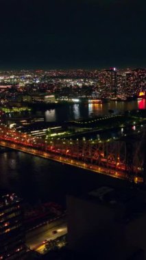 Queensboro Köprüsü 'nün güzel ışıklarıyla göz alıcı görüntüsü. Geceleri ışıklarla dolu inanılmaz bir şehir. Dikey video