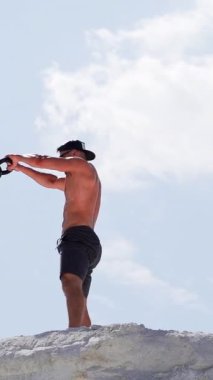 Dışarıda ağır bir ağırlıkla güçlü bir sporcunun antrenmanının yan görüntüsü. Kaslı sporcu bir günde yüksek tepede kettlebell sallıyor. Dikey video