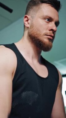 Spor kulübünde kol pazılarını çalıştıran konsantre bir sporcu. Genç sporcunun portresi halat çekerek modern bir simülatörde çalışıyor. Dikey video