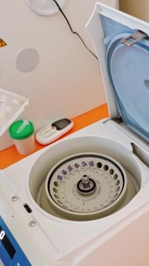 Laboratuvarda numuneleri kontrol etmek için modern bir cihaz. Mavi eldiven, santrifüj deliklerine kan testi yapılan plastik tüpleri yerleştirir. Dikey video