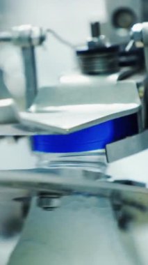 Plastik şişeyi kapakla kaplayan otomatik makine. Süt ürünleri. Modern bir fabrikada bir şişeyi sütle kaplamanın mekanik süreci. Dikey video