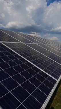 Bulutlu gökyüzünün altındaki güneş panelinin yakın çekimi. Alternatif enerji kaynağı. Yeşil çimlerin üzerindeki mavi güneş pili paneli. Ağır çekim. Dikey video
