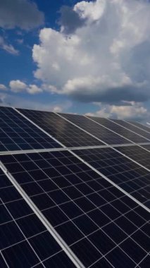 Elektrik santrali. Mavi gökyüzünün altında beyaz bulutlu güneş panelleri. Güneş enerjisi çiftliğinde alternatif elektrik kaynağı. Ekolojik yenilenebilir enerji kaynağı. Dikey video