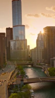 Gün batımında Chicago 'nun ayna binaları. Şikago nehri batan güneş ışınlarıyla. Hava görüntüsü. Dikey video