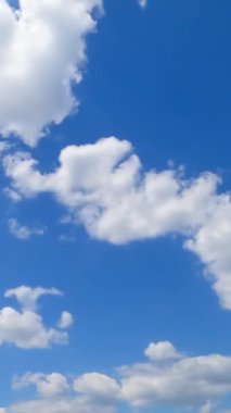 Mavi ufuk çizgisinde kabarık küçük bulutlar. Yazın gökyüzünde hareket eden bulutların müthiş zamanlaması. Dikey video