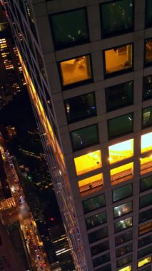 Geceleri gökdelende yükseklerde uçuyor. Milyarlarca ışıkla muhteşem New York manzarası. Üst Manzara. Dikey video