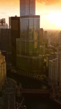 Chicago, Illinois, ABD 'de güneş batıyor. Gün batımında Chicago Nehri üzerinde İHA görüntüleri. Dikey video