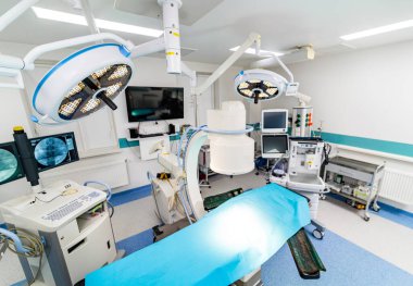 Mavi yataklı ve büyük ekranlı bir hastane odası. Oda aydınlık ve temiz.