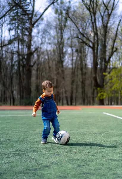 Young Boy Blue Overalls Kicks Soccer Ball Green Field Boy Imagini stoc fără drepturi de autor