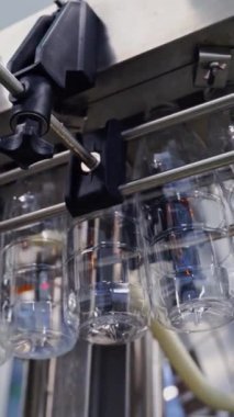 Konveyör hattında asılı duran boş plastik şişeler. Şişe üretim hattı. Modern süt fabrikasındaki sıvı için plastik şişelerden bak. Dikey video