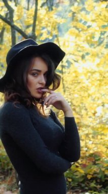 Parkta güneşli bir sonbahar günü. Genç bir kadın sonbahar parkında dikey video çekiyor.