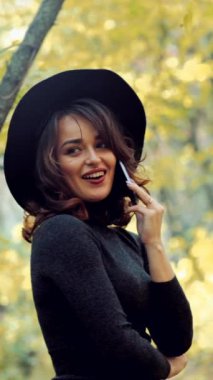 Parkta poz veren kadın. Sonbahar parkında poz veren mutlu genç kadın. Dikey video.