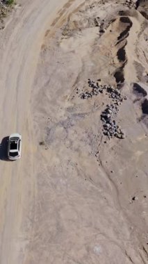 Göl kenarında araba sürüyor. Göl ve dağ kenarındaki yolun dikey görüntüsü