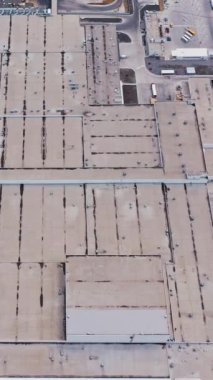 Birçok kamyonun ticaret mallarını yükleyip indirdiği Endüstriyel Depo Binası / Yükleme Alanının Hava Çekimi. Dikey video