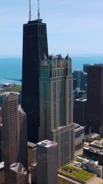 Chicago 'nun güzel gökdelenleri Michigan Gölü' nün rıhtımında duruyor. Mavi su ve gökyüzünün arkaplanındaki binaların havadan görüntüsü. Dikey video