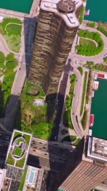 Chicago şehrinin yeşil bölgeleri ve gökdelenleri. Bir sürü araba geçen yoğun bir otoyol. Gölün deniz yeşili suyu. Kuş bakışı görüş. Dikey video