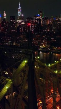 Rising above Ed Koch Queensboro Bridge with blinking red lights on tops. Incredible city panorama of vibrant New York at night. Vertical video