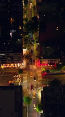 Crossroads with a number of cars at night time. Birds' eye view on the city traffic of New York. Vertical video